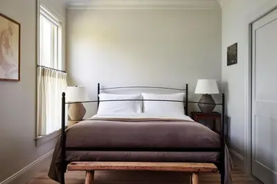 a bedroom with a bed with a wooden bench next to a window at Inness in Accord