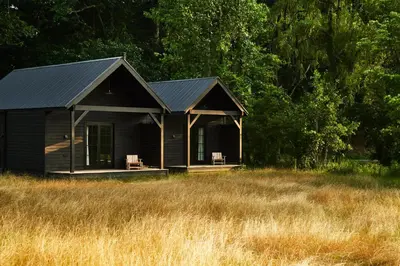 a black house with two chairs in a field at Inness in Accord