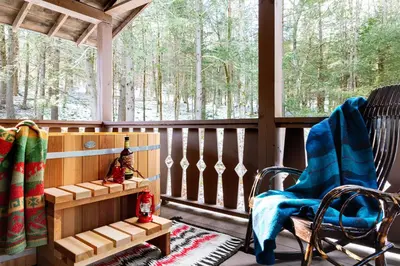 a screened in porch with a rocking chair and windows at Urban Cowboy Lodge in Big Indian