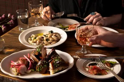 a wooden table with plates of food and glasses of wine at Urban Cowboy Lodge in Big Indian