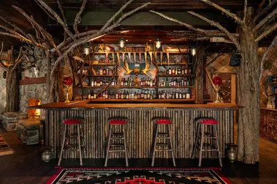 a bar with red stools in a room with trees at Urban Cowboy Lodge in Big Indian