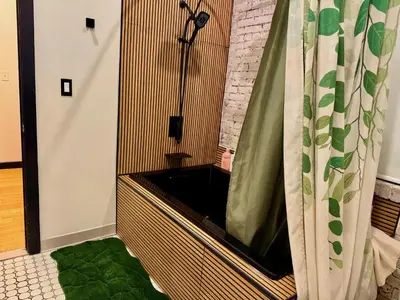 a bathroom with a bath tub with a green rug at Brick City Loft in Newark