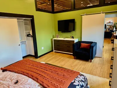 a bedroom with a bed and a chair and a television at Brick City Loft in Newark