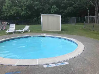 a large swimming pool in a yard with two chairs at Modern Home near Lake w HotTub, Game Room, Fireplace in Albrightsville