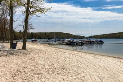 a sandy beach next to a lake with boats at 6 Fieldstone Ct in Lake Harmony