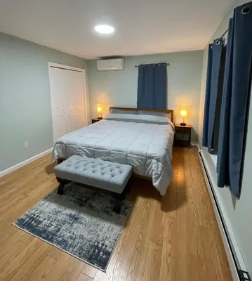a bedroom with a bed with a bench and blue curtains at Spacious Pocono Home with Hot Tub and Fire Pit in Long Pond