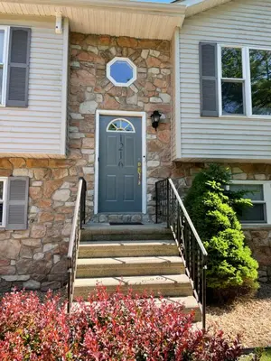a stone house with a blue door and stairs at Spacious Pocono Home with Hot Tub and Fire Pit in Long Pond
