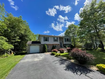 a house with a driveway in a yard at Spacious Pocono Home with Hot Tub and Fire Pit in Long Pond