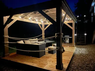 a gazebo with a couch on a deck at night at Spacious Pocono Home with Hot Tub and Fire Pit in Long Pond