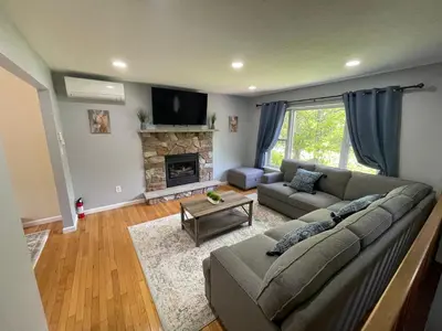 a living room with a couch and a fireplace at Spacious Pocono Home with Hot Tub and Fire Pit in Long Pond