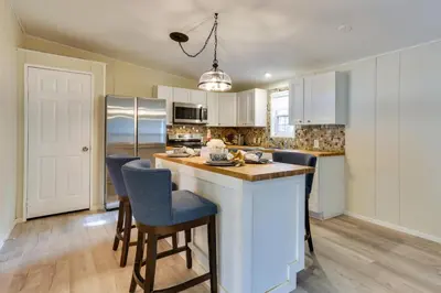 a kitchen with white cabinets and a island with bar stools at Kayaks, Electric Bicycles Greentown Hideaway! in Greentown