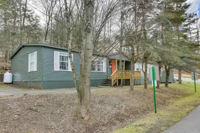 a blue house with a porch in the woods at Kayaks, Electric Bicycles Greentown Hideaway! in Greentown