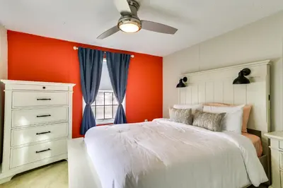 a bedroom with an orange wall and a white bed at Kayaks, Electric Bicycles Greentown Hideaway! in Greentown