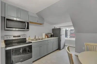 a kitchen with stainless steel appliances and a table at Suites on Seneca - Gorgeous One Bedroom Apartment in Harrisburg
