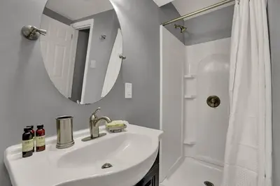 a white bathroom with a sink and a mirror at Suites on Seneca - Gorgeous One Bedroom Apartment in Harrisburg