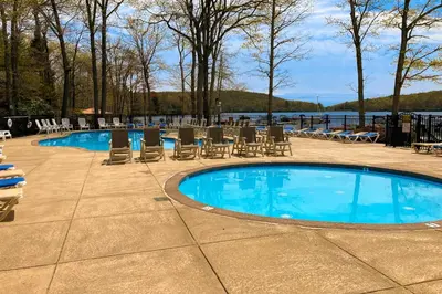 a swimming pool with chairs and a table and water at Midlake Memories in Lake Harmony