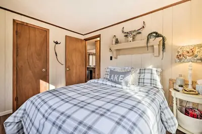 a bedroom with a bed with a blue and white checked blanket at Fire Pit and Grill Woodside Nest in Pocono Lake! in Pocono Lake
