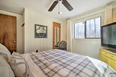 a bedroom with a bed and a flat screen tv at Fire Pit and Grill Woodside Nest in Pocono Lake! in Pocono Lake