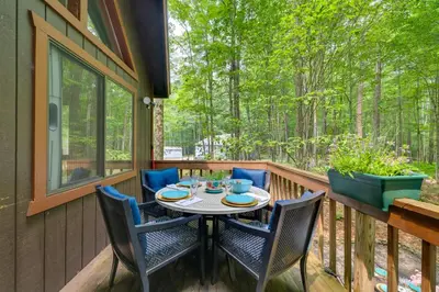 a patio with a table and chairs on a deck at Fire Pit and Grill Woodside Nest in Pocono Lake! in Pocono Lake
