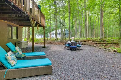 a patio with chairs and a table in the woods at Fire Pit and Grill Woodside Nest in Pocono Lake! in Pocono Lake