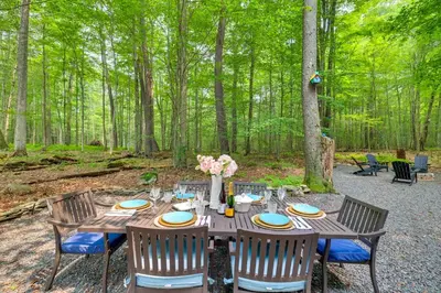 a wooden table with chairs and flowers on it at Fire Pit and Grill Woodside Nest in Pocono Lake! in Pocono Lake
