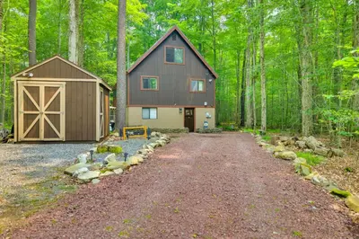 a large barn with a driveway in the woods at Fire Pit and Grill Woodside Nest in Pocono Lake! in Pocono Lake