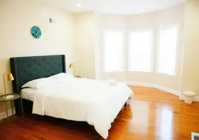 a bedroom with a bed with white sheets and windows at Newly Renovated Guest Rooms near Transportation in Philadelphia