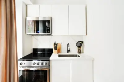 a white kitchen with a sink and a microwave at 69-2C Brand New PRIME Lower East Side 1br Apt in New York