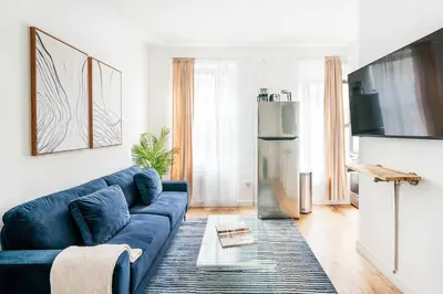 a living room with a blue couch and a refrigerator at 69-2C Brand New PRIME Lower East Side 1br Apt in New York