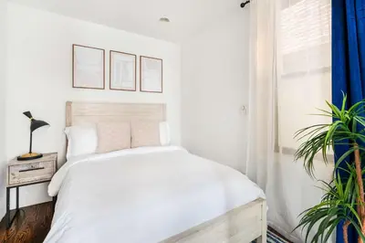 a white bedroom with a bed and a plant at 69-3A Prime LES Modern Brand New 1BR in New York