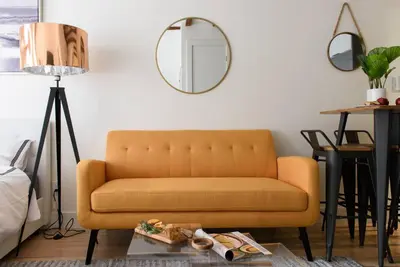 a living room with a yellow couch and a mirror at 24-14 Renovated studio Prime gramercy W D in New York