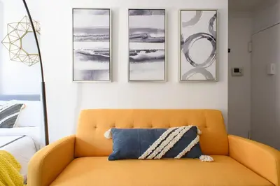 an orange couch in a room with four pictures on the wall at 24-16 Studio Gramercy W D gramercy in New York
