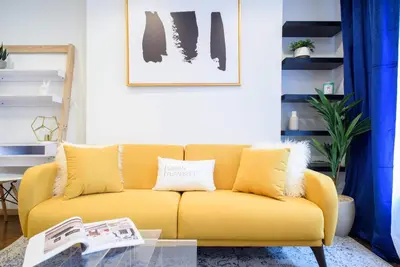 a yellow couch in a living room with a glass table at 69-4A Quality NEW Prime Lower East East 1br Apt in New York