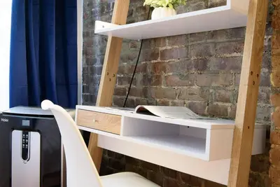 a desk with a chair next to a brick wall at 24-17 Renovated Studio Prime Location WD in New York