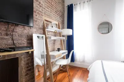 a bedroom with a brick wall and a bed and a chair at 24-18 New Gramercy Studio W D in Unit Fully Reno in New York