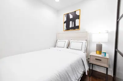 a white bedroom with a bed and a night stand at 69-4C PRIME Lower East Side 1br Apt Brand New in New York