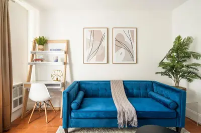 a blue couch in a living room with a plant at 69-4D Trendy Lower East Side 1B BRAND NEW in New York
