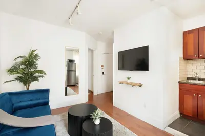 a living room with a blue chair and a tv at 69-4D Trendy Lower East Side 1B BRAND NEW in New York
