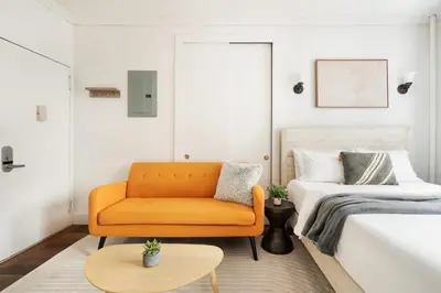 a living room with an orange couch and a bed at 24-4 New Private Terrace W D Apt Prime Gramercy in New York