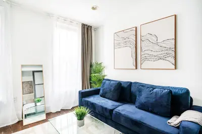 a living room with a blue couch and a mirror at 69-5B I Stylish Lower East Side 1BR Apt BRAND NEW in New York