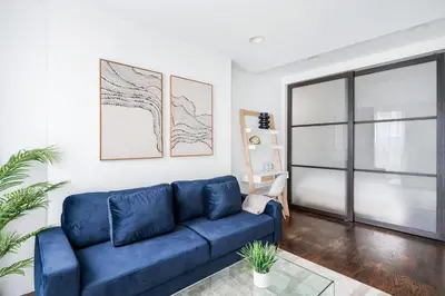 a blue couch in a living room with a window at 69-5B I Stylish Lower East Side 1BR Apt BRAND NEW in New York