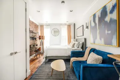 a living room with a blue couch and a bed at 24-5 Furnished Studio W D Prime Gramercy in New York