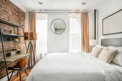 a bedroom with a white bed and a brick wall at 24-5 Furnished Studio W D Prime Gramercy in New York