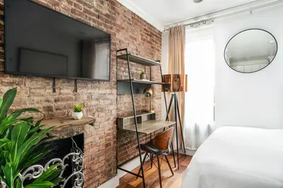 a bedroom with a brick wall with a tv above a fireplace at 24-5 Furnished Studio W D Prime Gramercy in New York