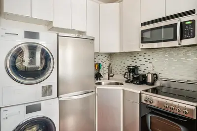 a kitchen with stainless steel appliances and white cabinets at 24-5 Furnished Studio W D Prime Gramercy in New York