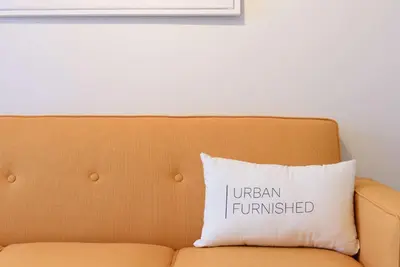 an orange couch with a pillow that reads unseenfunded at 69-5D Modern Lower East East 1br Apt BRAND NEW in New York