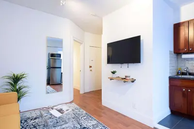 a kitchen with a flat screen tv on a white wall at 69-5D Modern Lower East East 1br Apt BRAND NEW in New York