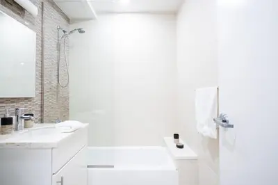 a white bathroom with a shower and a sink at 809-3B Columbus Circle W D new BLDG Balcony in New York