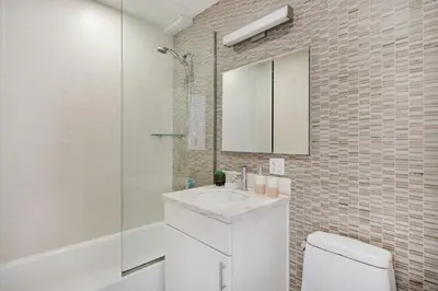 a white bathroom with a sink and a mirror at 809-4A Columbus Circle New BLDG 1BR W D in New York