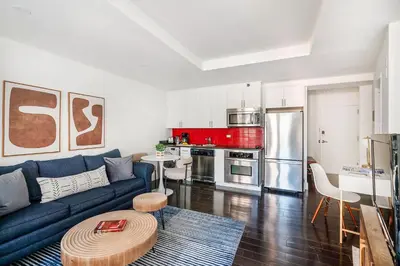a living room with a blue couch and a kitchen at 809-4B Studio Balcony W D Prime location in New York